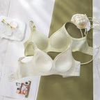 Top down display of Two bras, one milky green and one white, with decorative elements.